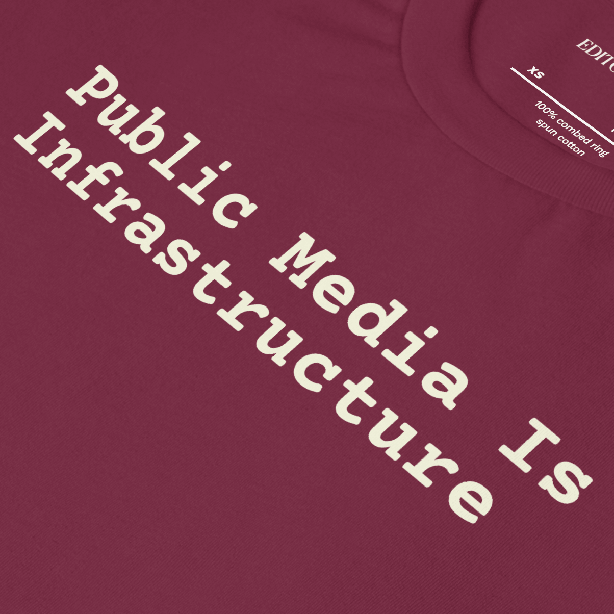 Public Media Is Infrastructure printed on a maroon tee shirt, promoting the importance of Public Media.